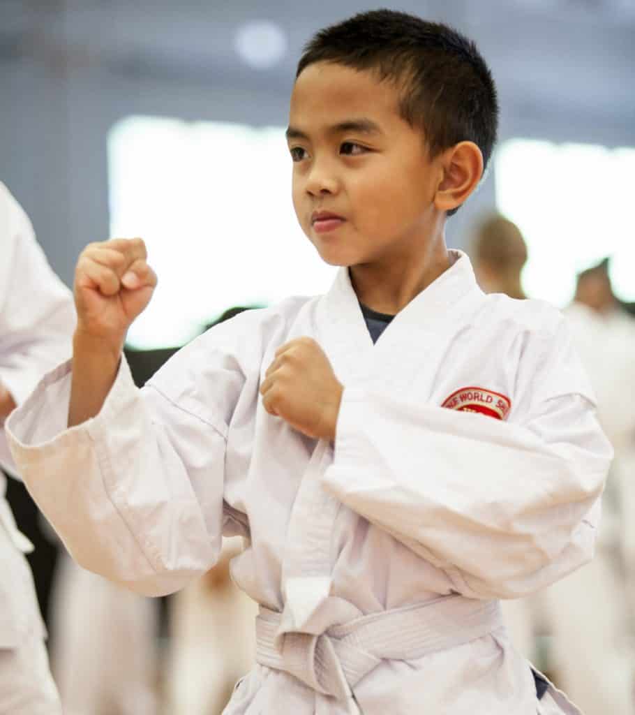 young white belt boy learning how to hold a strong guard, karate for all ages