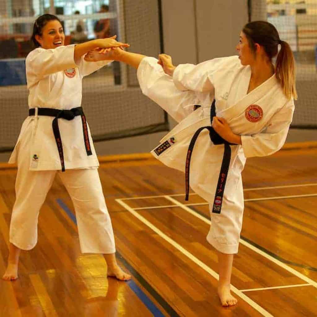 mother and daughter black belts practicing a head kick and block