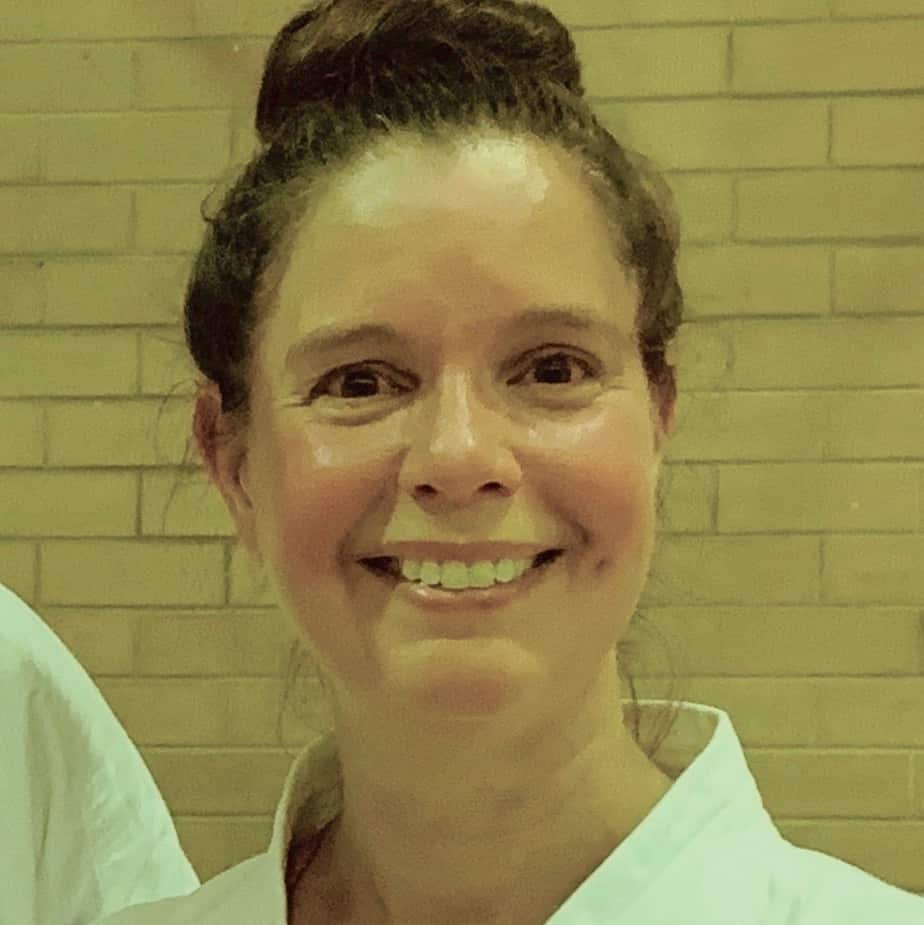 head shot of a woman in karate gear smiling at the camera